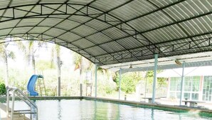 Una piscina al coperto con tettoia, una scala e uno scivolo blu.