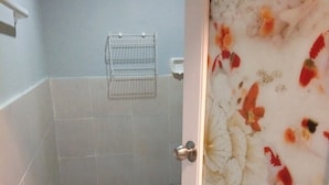 Un bagno con pavimento piastrellato, zona doccia e porta decorata con un motivo a pesce.