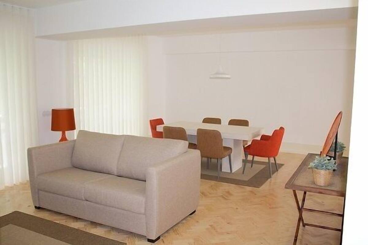 A living room with a sofa, dining table, chairs, and a lamp.