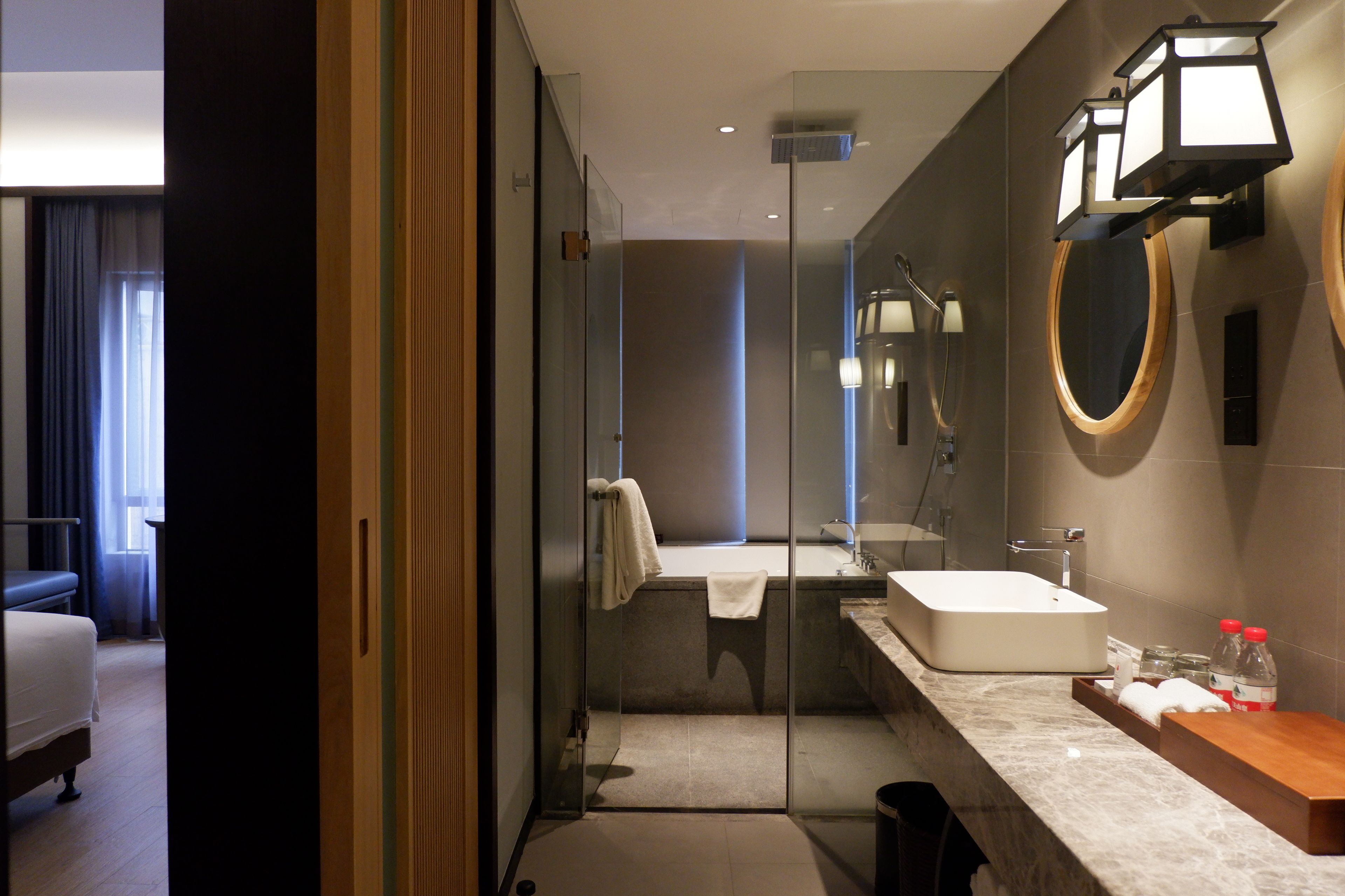 A modern bathroom with a glass shower enclosure, a large mirror, and a marble countertop.