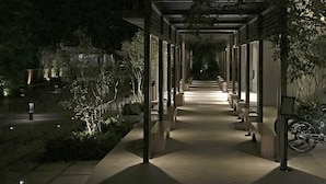 A covered walkway with benches, surrounded by greenery and a bicycle. - The Lucid Resort (Taizhou)