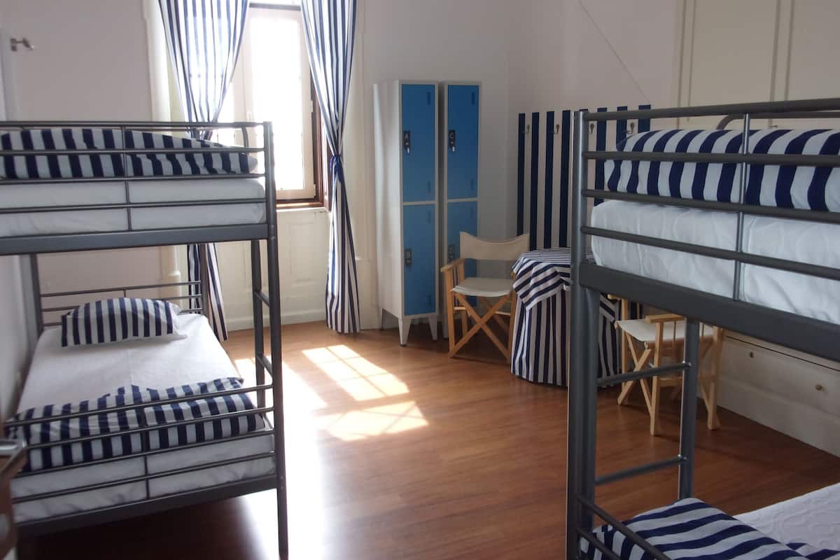 A dormitory room with bunk beds, a desk, and a chair.