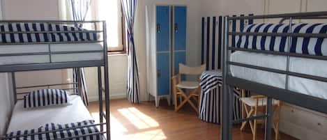 A dormitory room with bunk beds, a desk, and a chair.