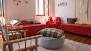Una habitación con dos camas, una silla de madera, un sillón de pícea y un ventanal con vistas.