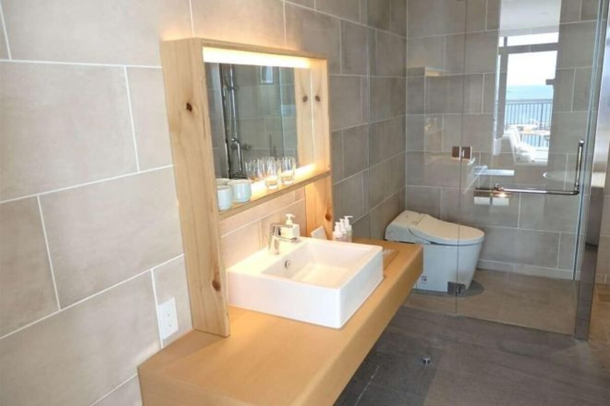A modern bathroom with a large sink, mirror, and glass shower enclosure.