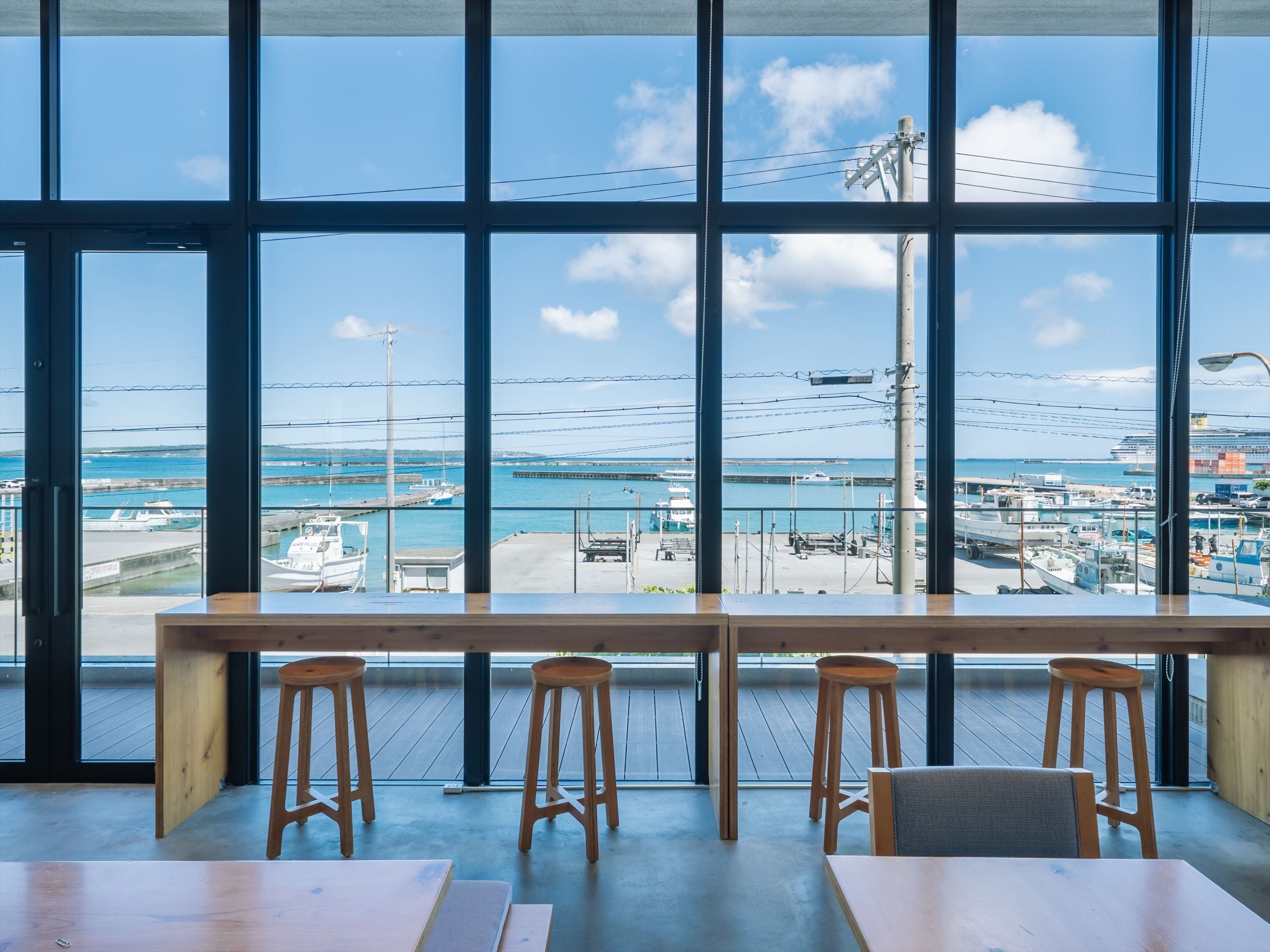 Un restaurant doté de grandes fenêtres donnant sur un port de plaisance et la mer.