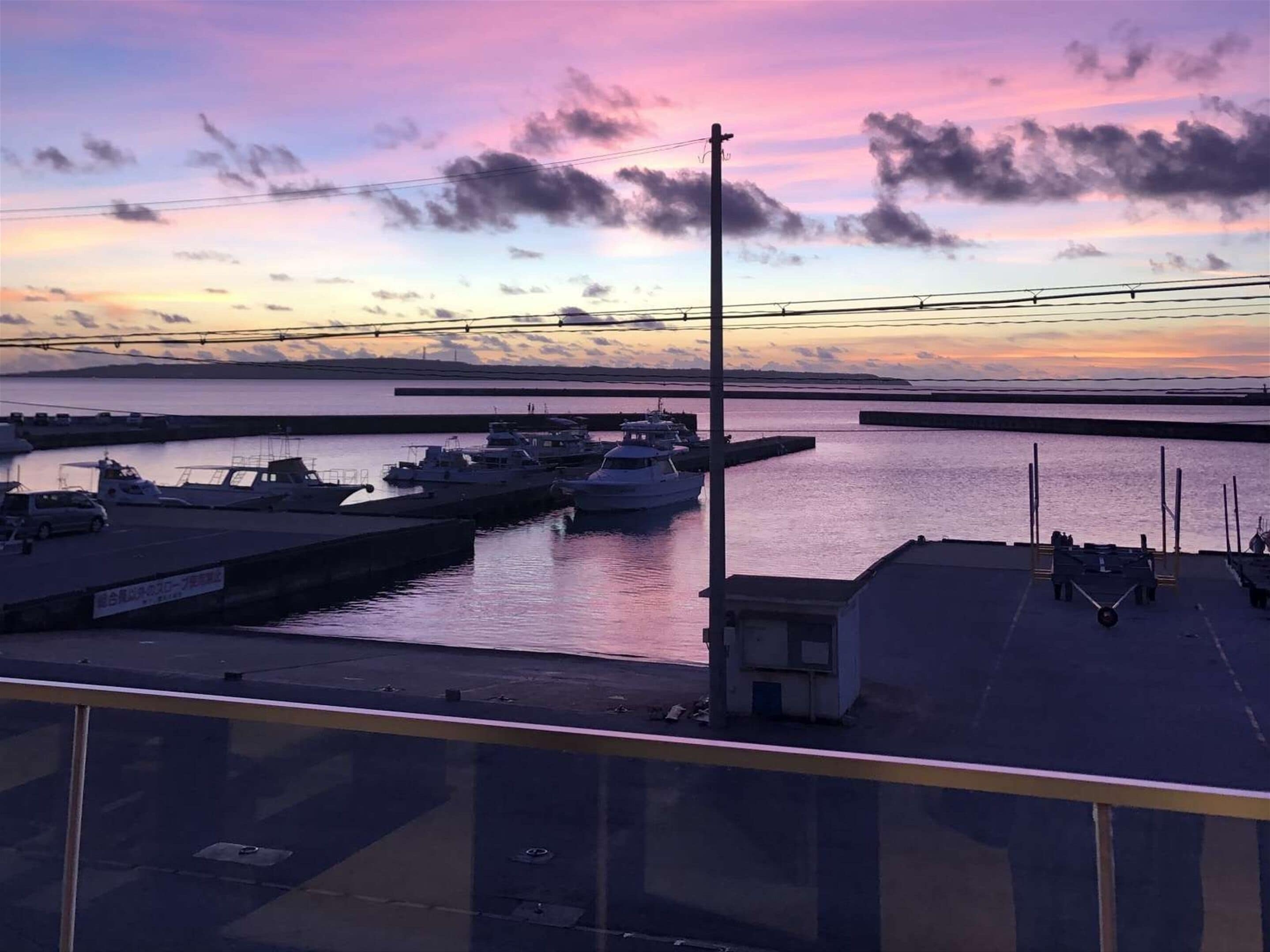 A marina with boats docked, a clear sky, and a sunset.
