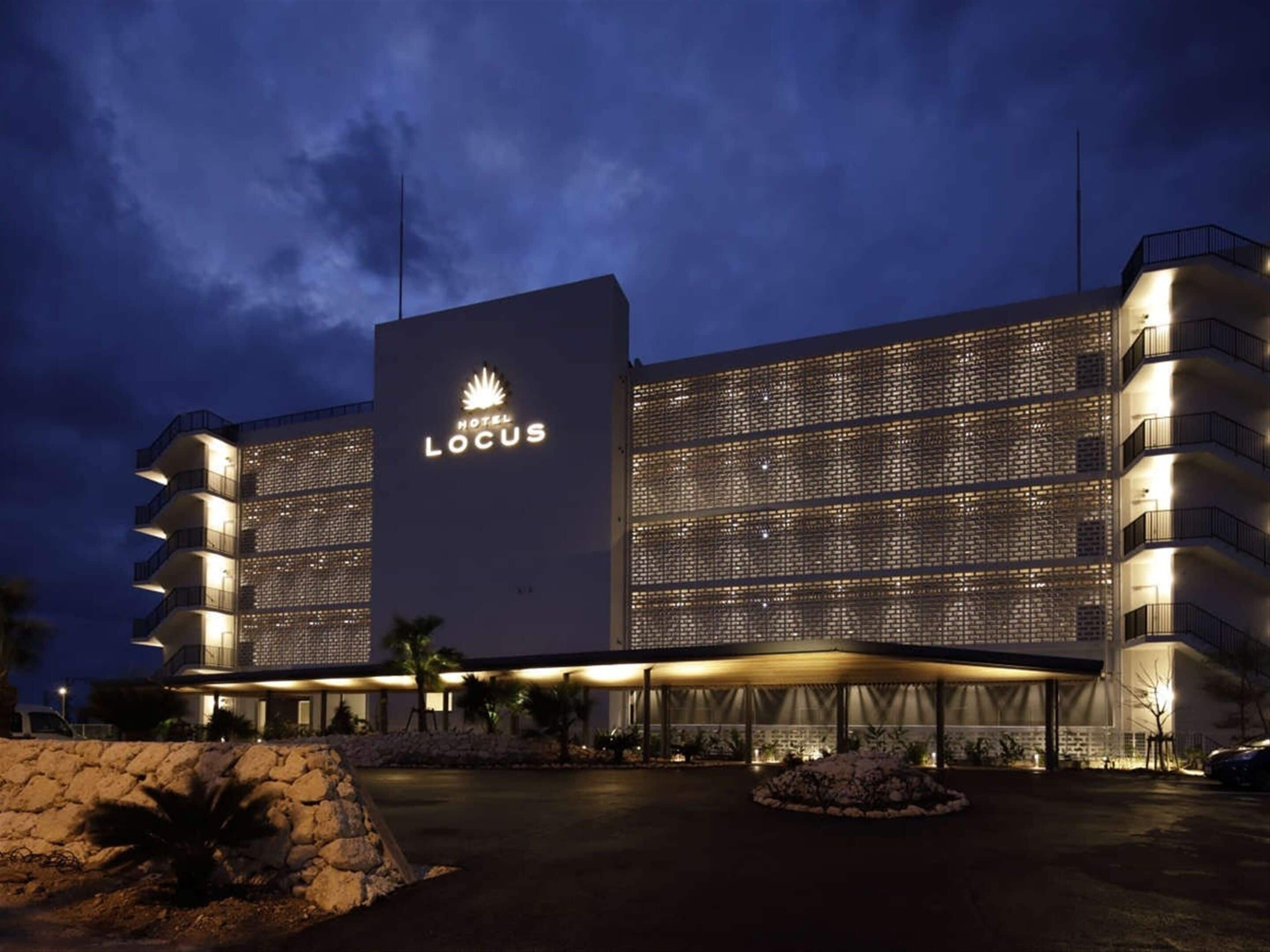 A hotel with a prominent sign reading "HOTEL LOCUS" and a modern architectural design featuring multiple balconies and a covered entrance.