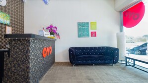 Una zona de recepción con una pared con diseño de mosaico, un sofá azul oscuro y carteles motivacionales.