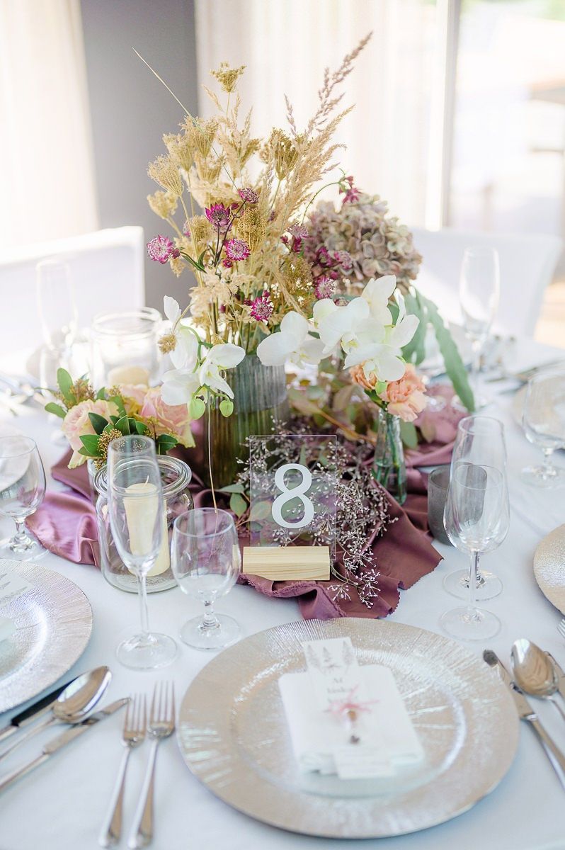 Una mesa dispuesta para un evento formal, con un centro de mesa de flores, velas y un número.