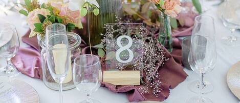 A table set for a formal event with a centerpiece of flowers, candles, and a number sign.