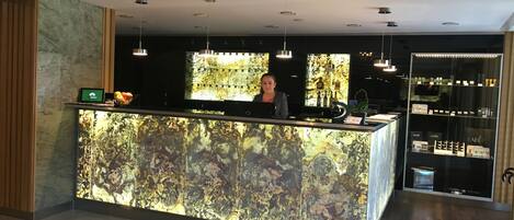 A reception desk with a marble-like surface, a digital screen, and a fruit bowl.