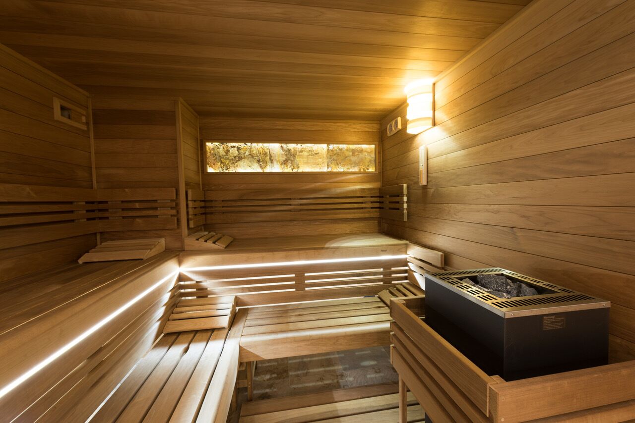 A sauna with wooden benches and a central heating unit.