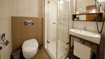 A modern bathroom with a glass-enclosed shower, a white toilet, a sink with a mirror, and a towel rack.