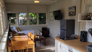 Cocina compacta con mesa y sillas, refrigerador y televisor en la pared.
