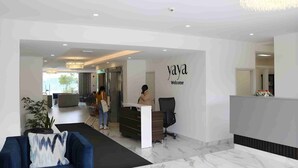 A modern reception area with a reception desk, a blue sofa, and a chandelier. - Yaya Hotel and Apartments (Nairobi)