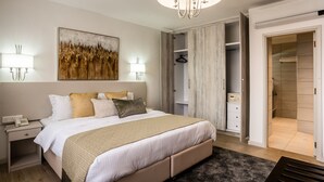 A modern bedroom with a large bed, bedside lamps, a chandelier, a wardrobe, and a walk-in closet. - Yaya Hotel and Apartments (Nairobi)