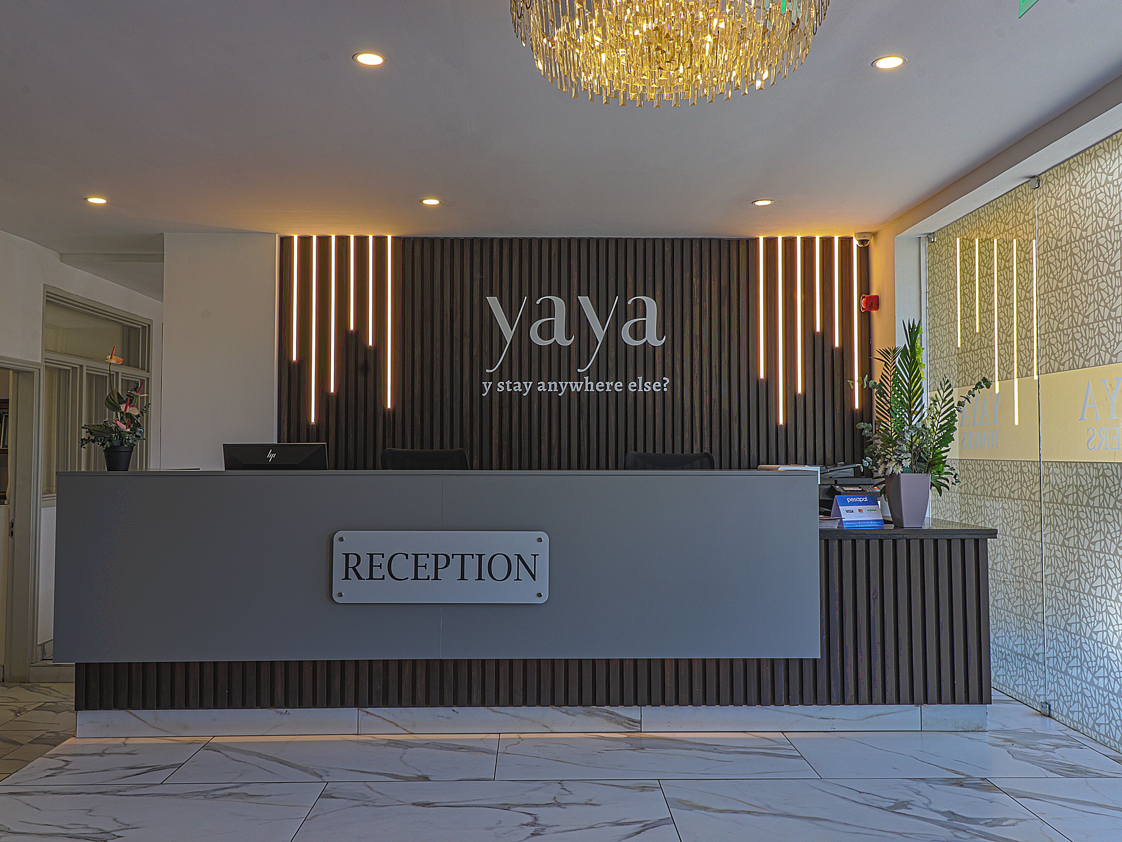 Een receptiebalie met een bordje met de tekst 'RECEPTION' en de naam 'yaya' erboven.