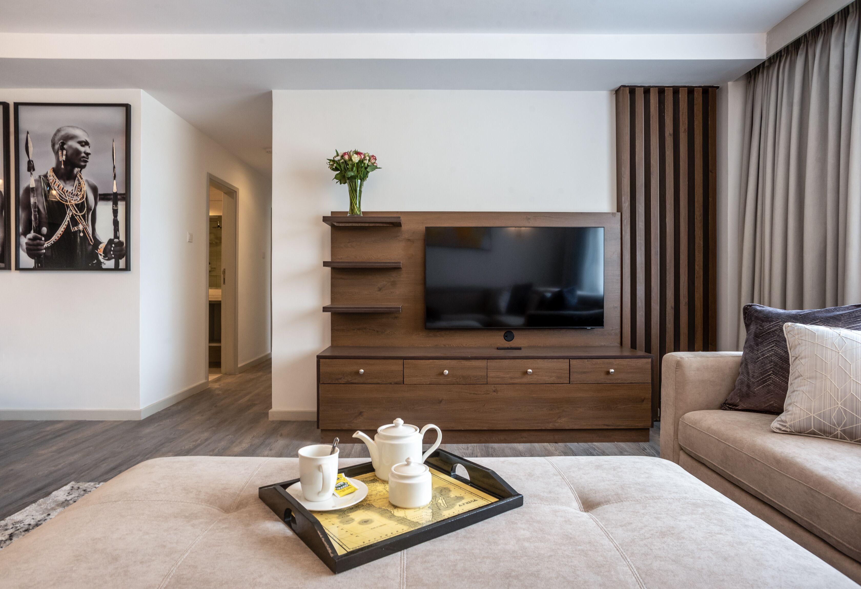 Een moderne woonkamer met een flatscreen televisie, een houten tv-meubel en een bank.