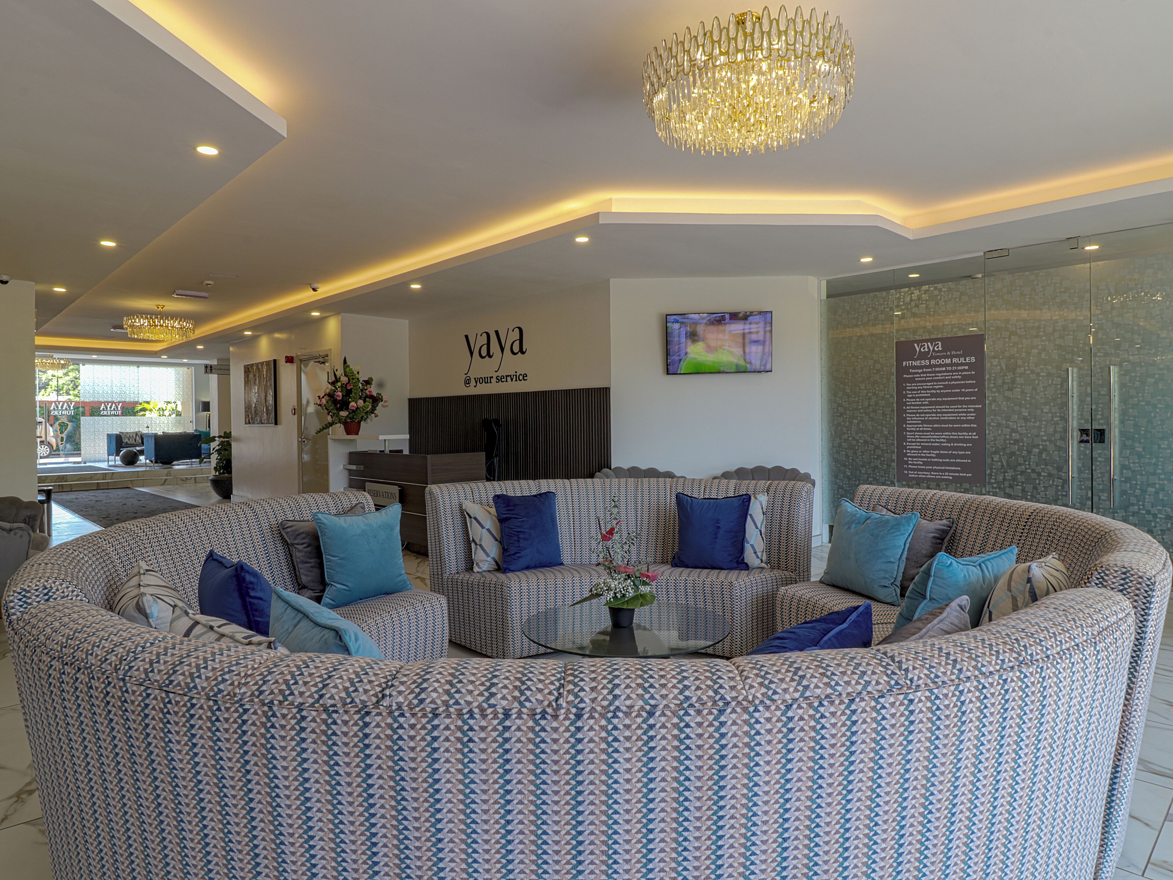 A modern living area with a curved sofa set, a chandelier, and a wall-mounted TV.