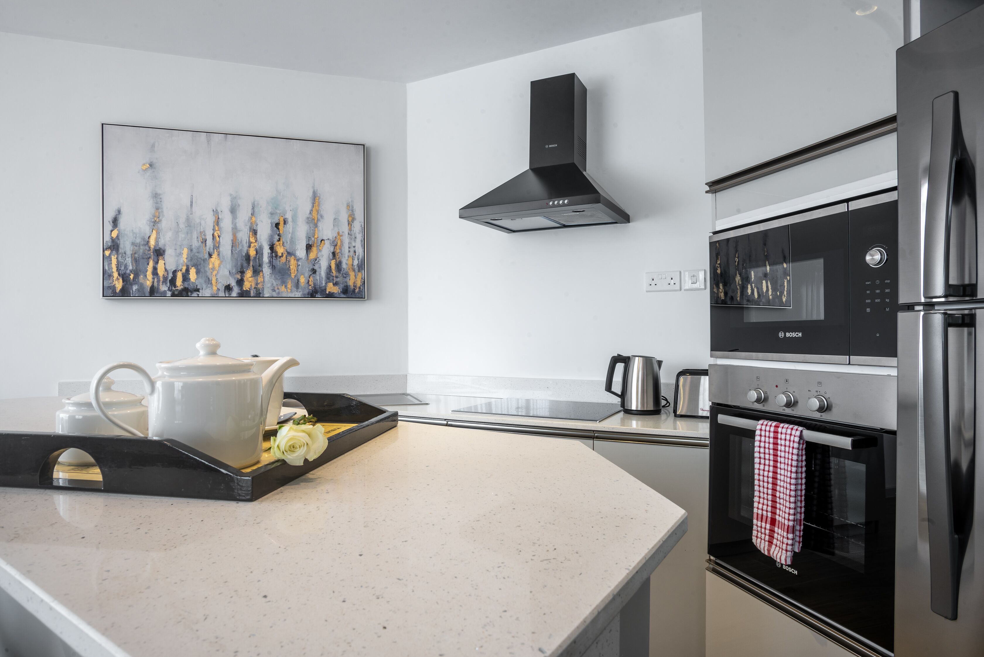 A modern kitchen with a Bosch oven, a microwave, and a stainless steel range hood.
