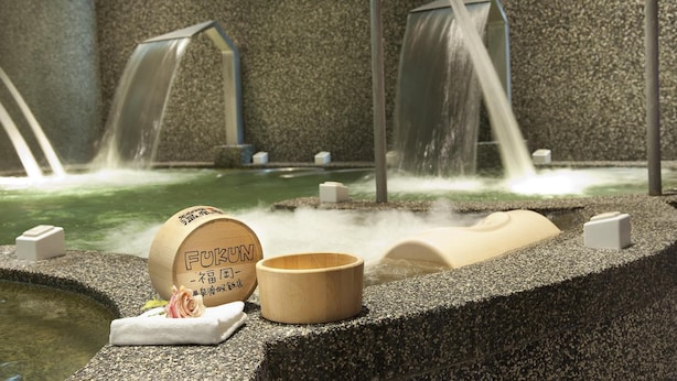 A spa area with a stone bath, a wooden bucket labeled "FUKUN," and a small wooden cup. - Fukun 5 Motel (Jiaoxi)