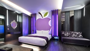 A modern hotel room with a large bed, a sofa, a mirror, and a wall with an apple logo. - Fukun 5 Motel (Jiaoxi)