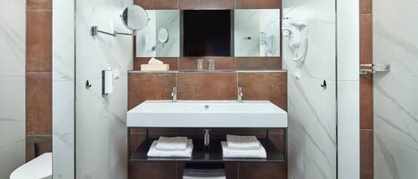 A modern bathroom with a large sink, two mirrors, a hairdryer, and a toilet.