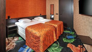 A hotel room with a bed, a nightstand, a TV, and a door.