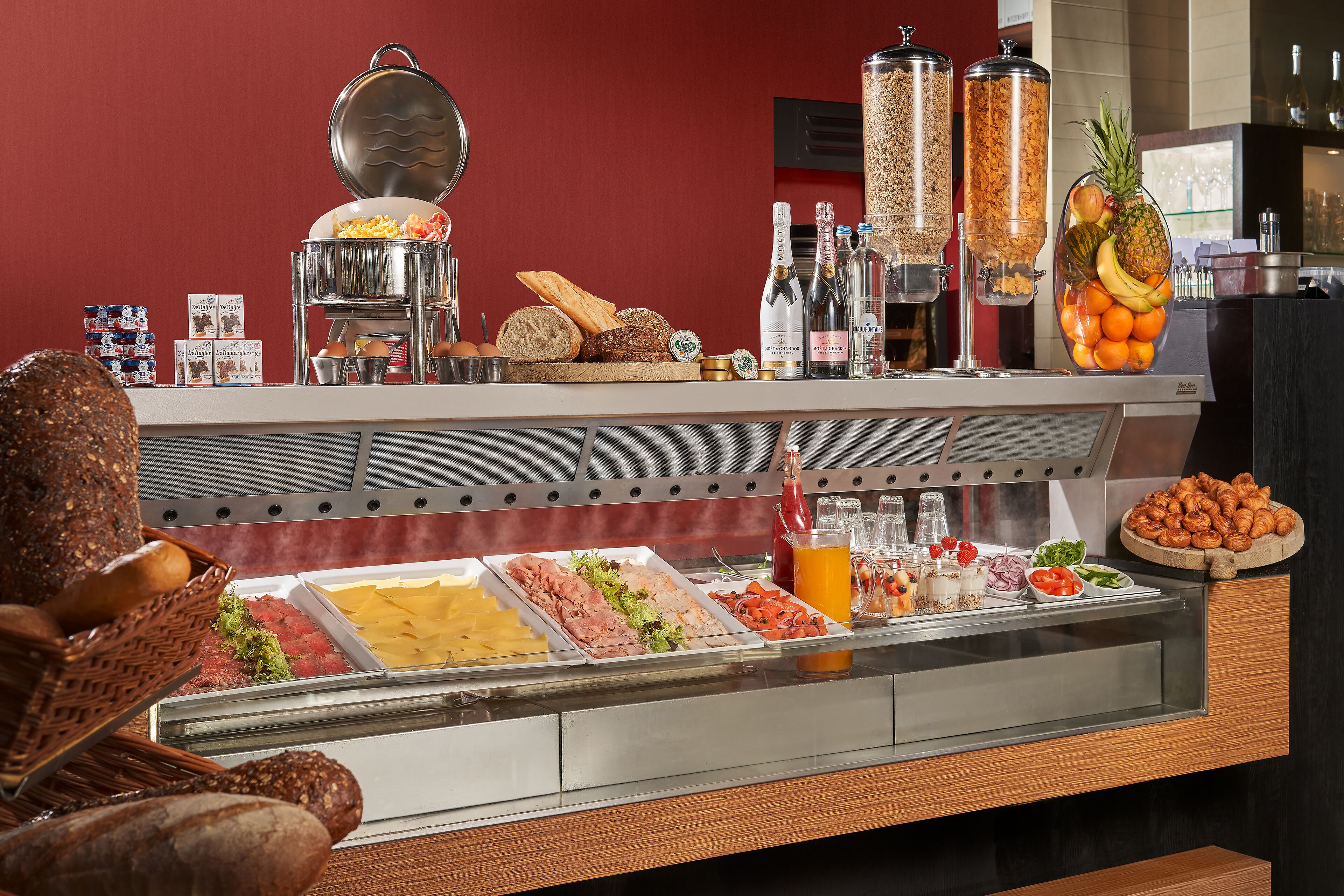A buffet with various food items, including meats, cheeses, and fruits, and a selection of beverages.