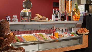 A buffet with various food items, including meats, cheeses, and fruits, and a selection of beverages.