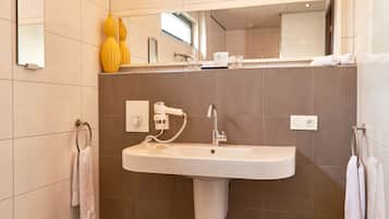 Un bany modern amb un lavabo gran, un mirall i dos vasetes grogues a la superfície.
