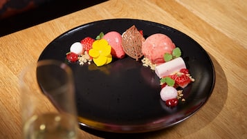 Une assiette de dessert avec divers fruits et un verre de vin sur une table en bois.
