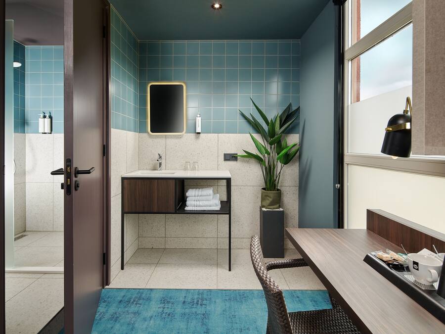 A modern bathroom with a sink, mirror, and potted plant.