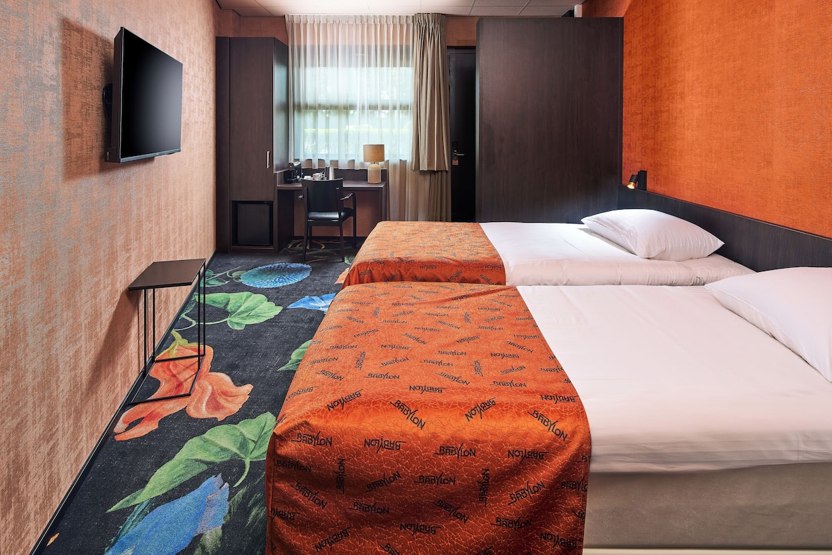 A hotel room with a bed, a desk, a chair, and a television.