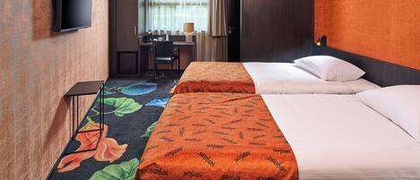 A hotel room with a bed, a desk, a chair, and a television.