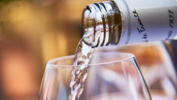 Una copa de vino siendo servida con líquido transparente, probablemente vino, desde una botella.