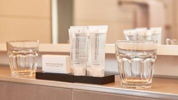 A bathroom counter with spa collection products, including bottles and a box, and two glasses of water.