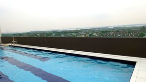 Piscina con vistas a edificios lejanos y zonas verdes.