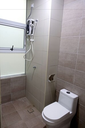 A small, tiled bathroom with a toilet, a shower unit, and a window. - D'Carlton Resort (Masai)