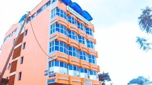 A multi-story hotel with a distinctive orange facade and blue accents. - Gemco Lodge (Embu)