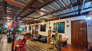 A spacious indoor area with a high ceiling, tiled floor, and a variety of seating arrangements including chairs and a sofa.