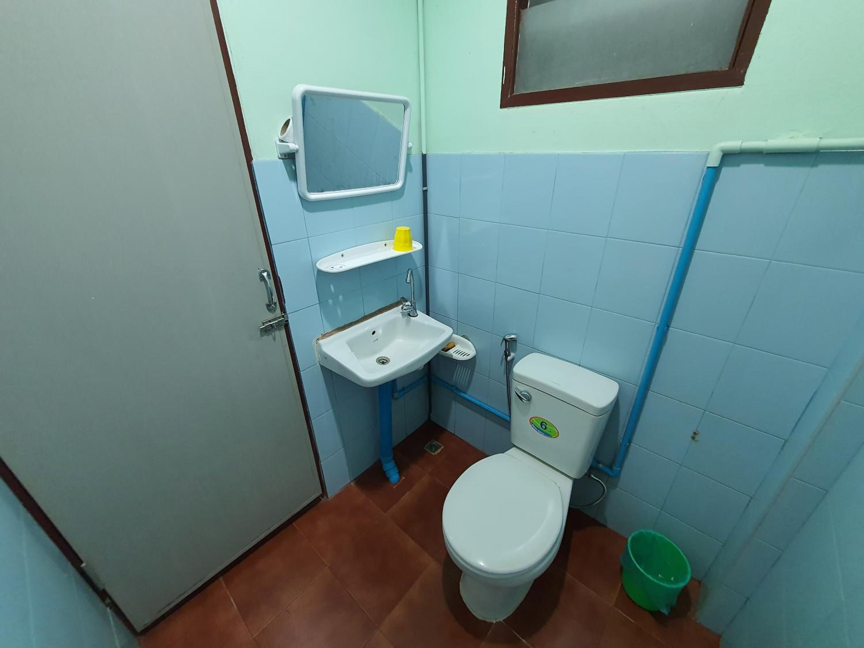 A small bathroom with a toilet, sink, and a mirror.