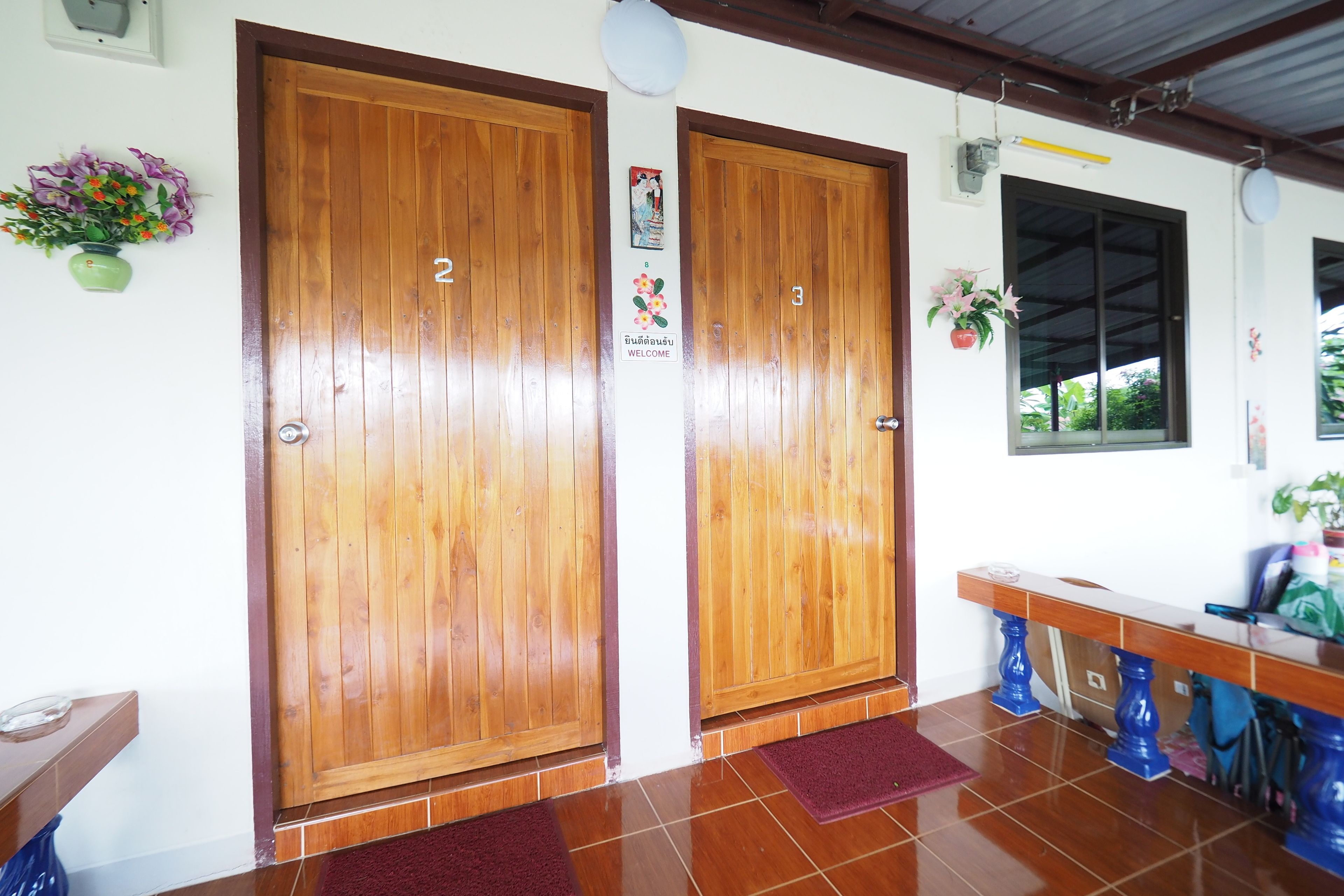 A wooden door with a welcome sign, a bench, and a window with a view.