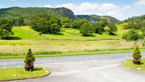 A rural landscape with a road, stone walls, and green fields.