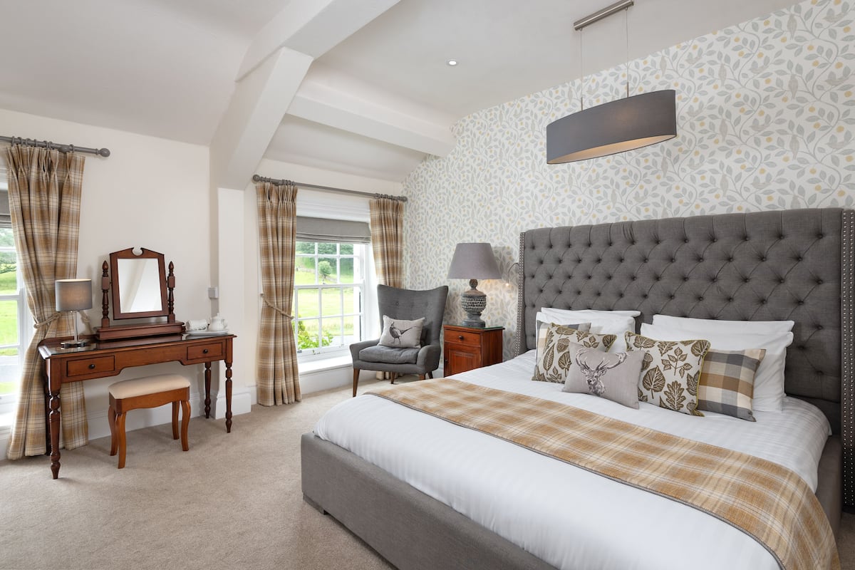 A bedroom with a large bed, a wooden dresser, a chair, and a nightstand.
