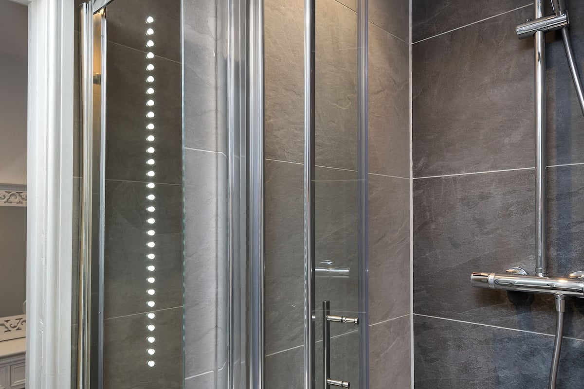 A modern bathroom with a glass-enclosed shower, a white sink, and a large mirror.