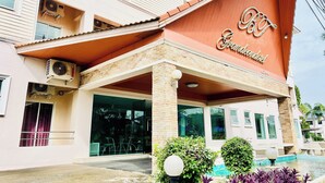 A hotel with a red facade, a covered entrance, and a swimming pool area. - BT Grand Condotel (Udon Thani)