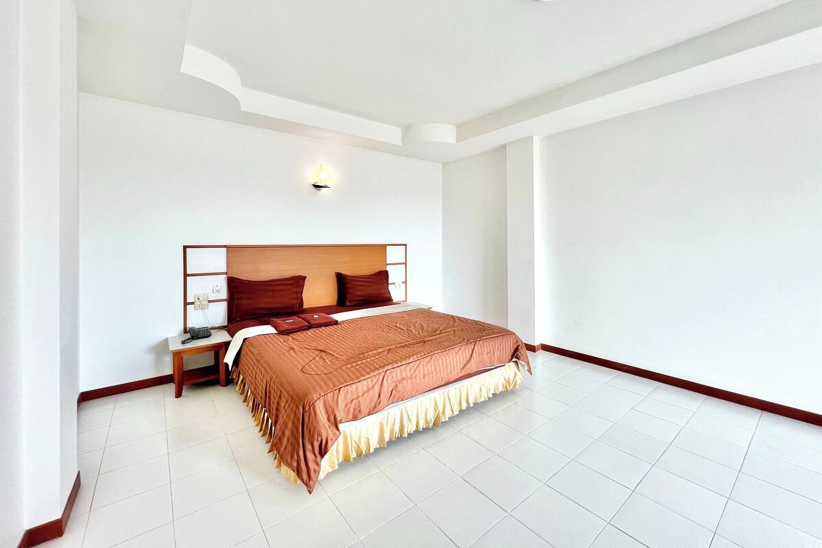 A modern hotel room with a large bed, a bedside table, and a nightstand.