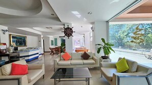 A modern living room with a sofa, coffee table, and a dining area in the background. - BT Grand Condotel (Udon Thani)